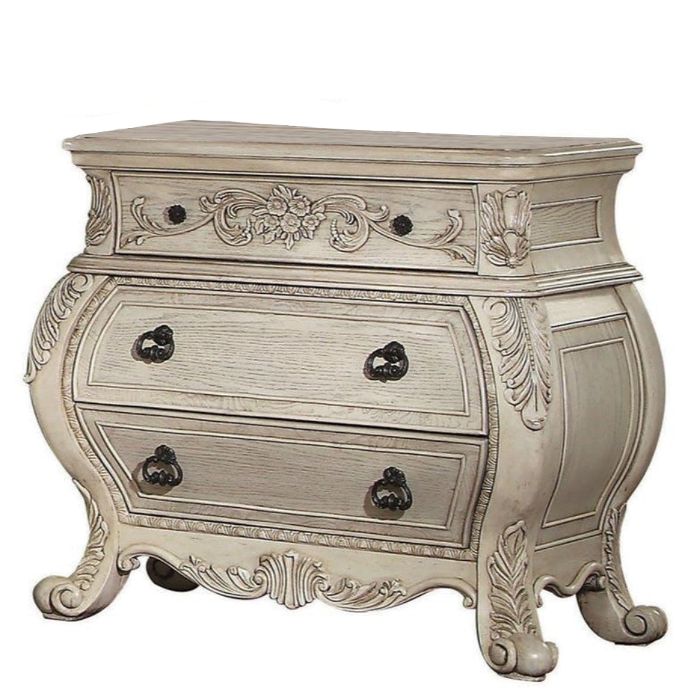 Three-drawer wooden nightstand with scrolled feet in antique white finish.