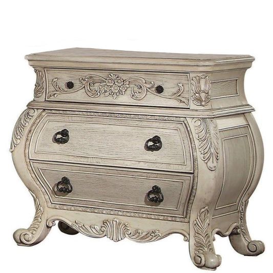 Three-drawer wooden nightstand with scrolled feet in antique white finish.