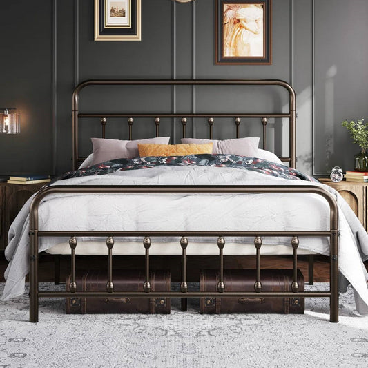 Full size vintage bronze metal platform bed frame with headboard and footboard; white bedding and two suitcases beneath.