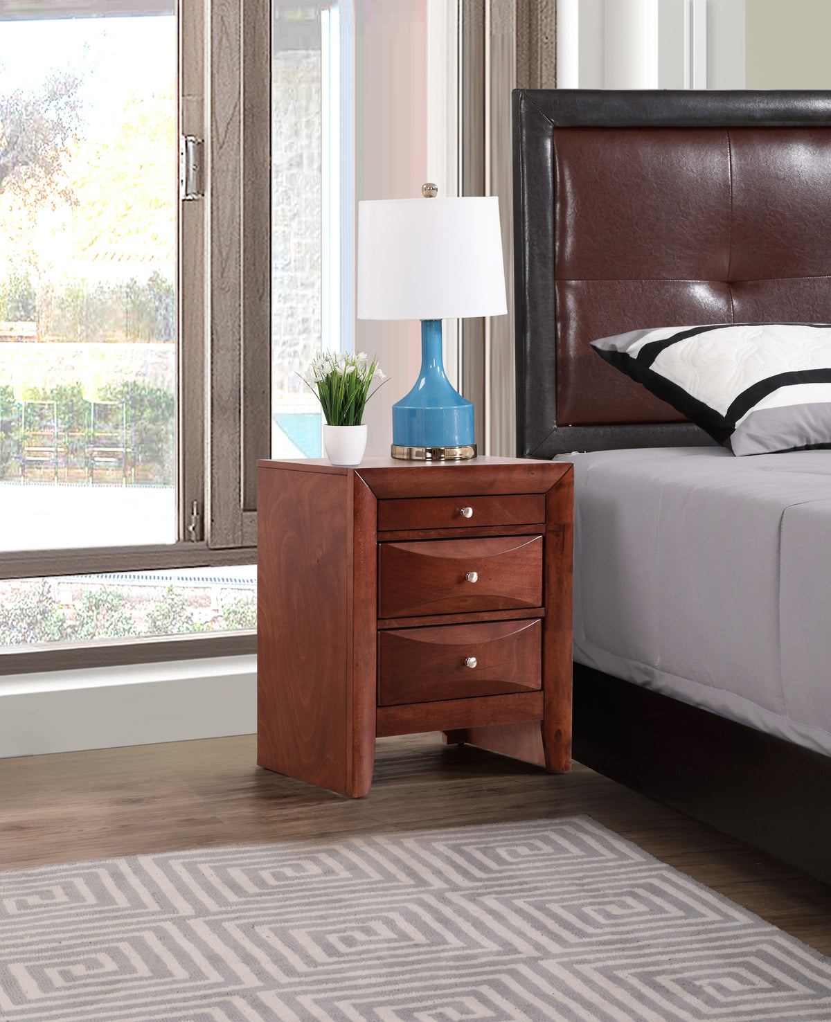 Sleek cherry nightstand with storage, four drawers and silver hardware, beside a blue lamp in a contemporary bedroom.