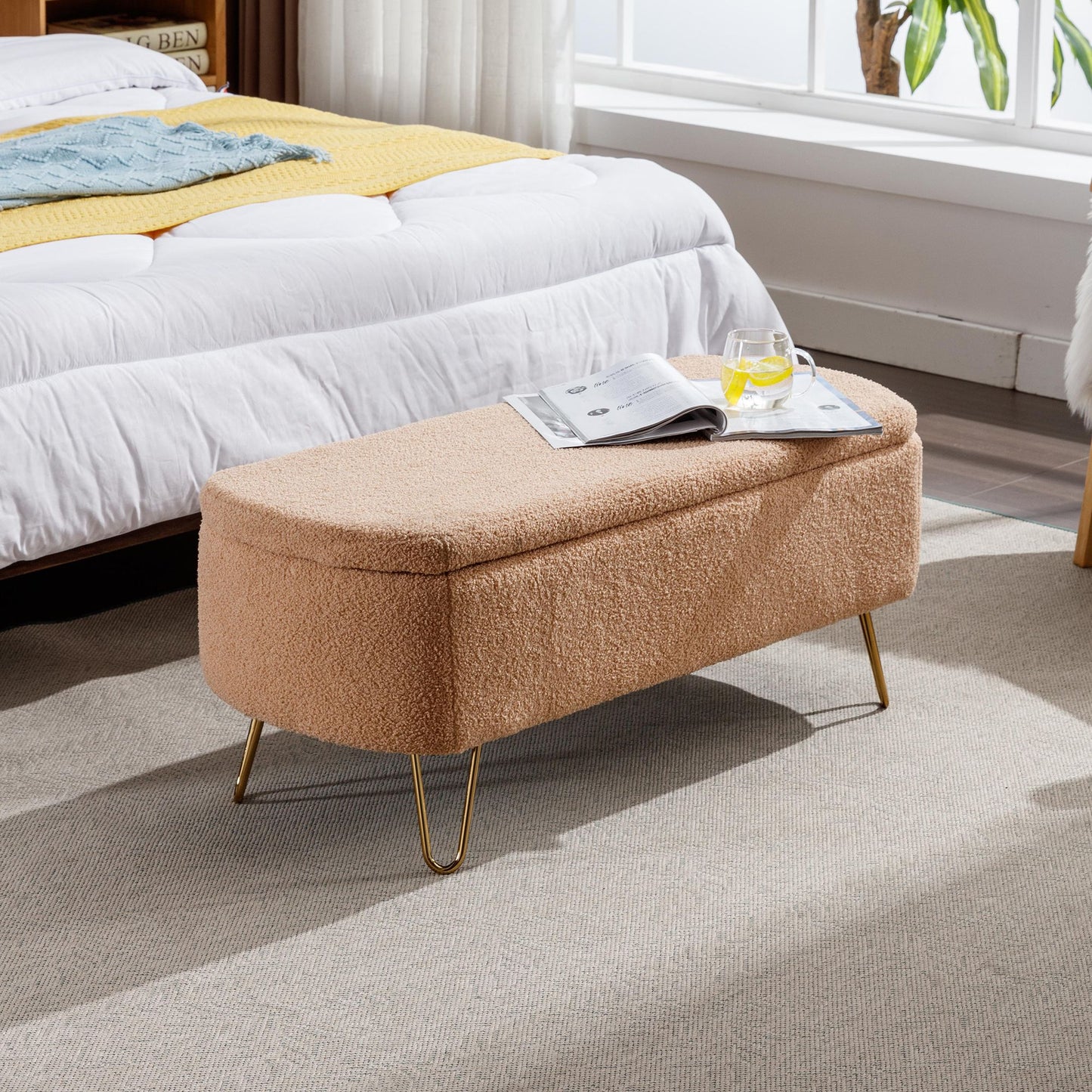 Camel faux-fur storage ottoman bench with gold legs at end of bed.