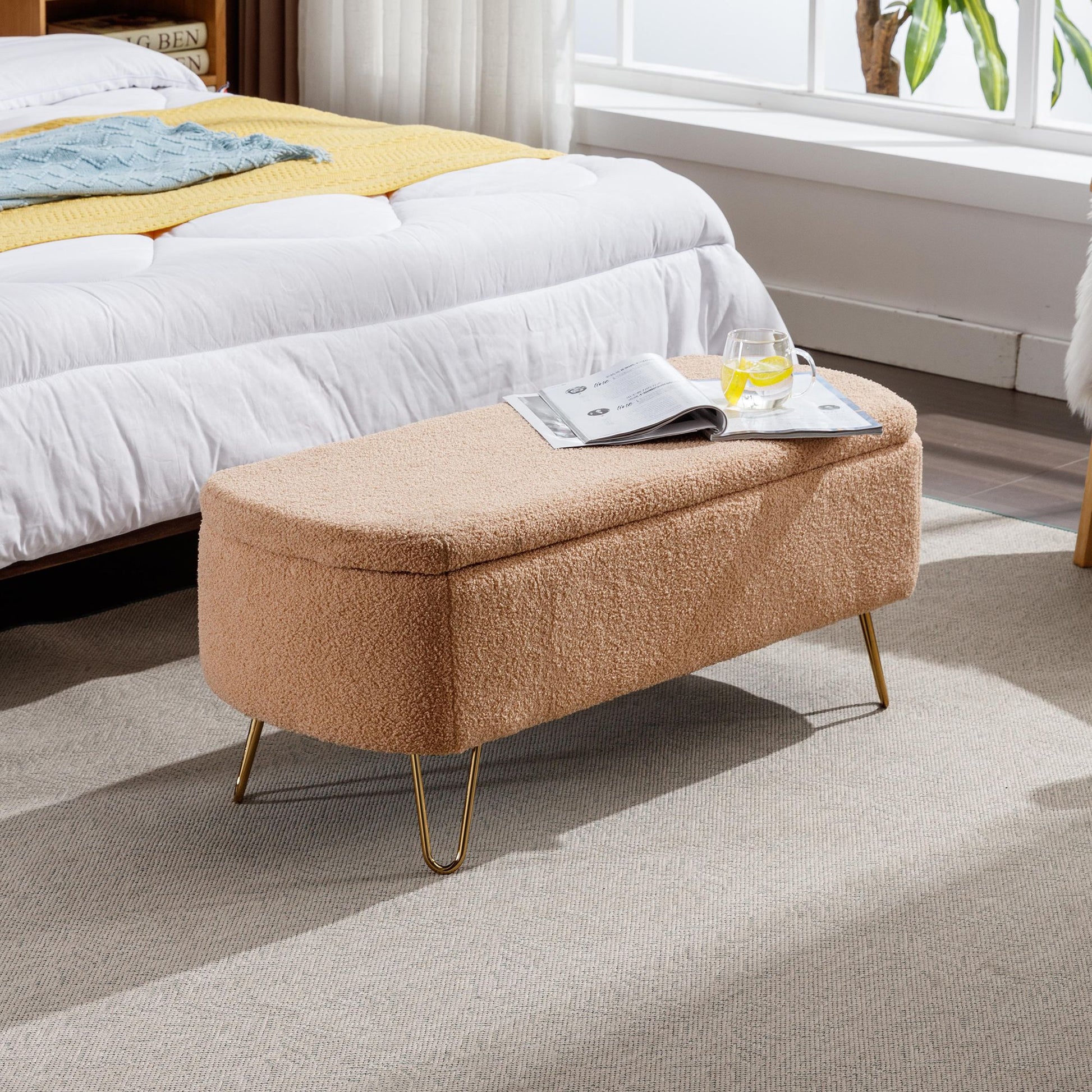 Camel faux-fur storage ottoman bench with gold legs at end of bed.