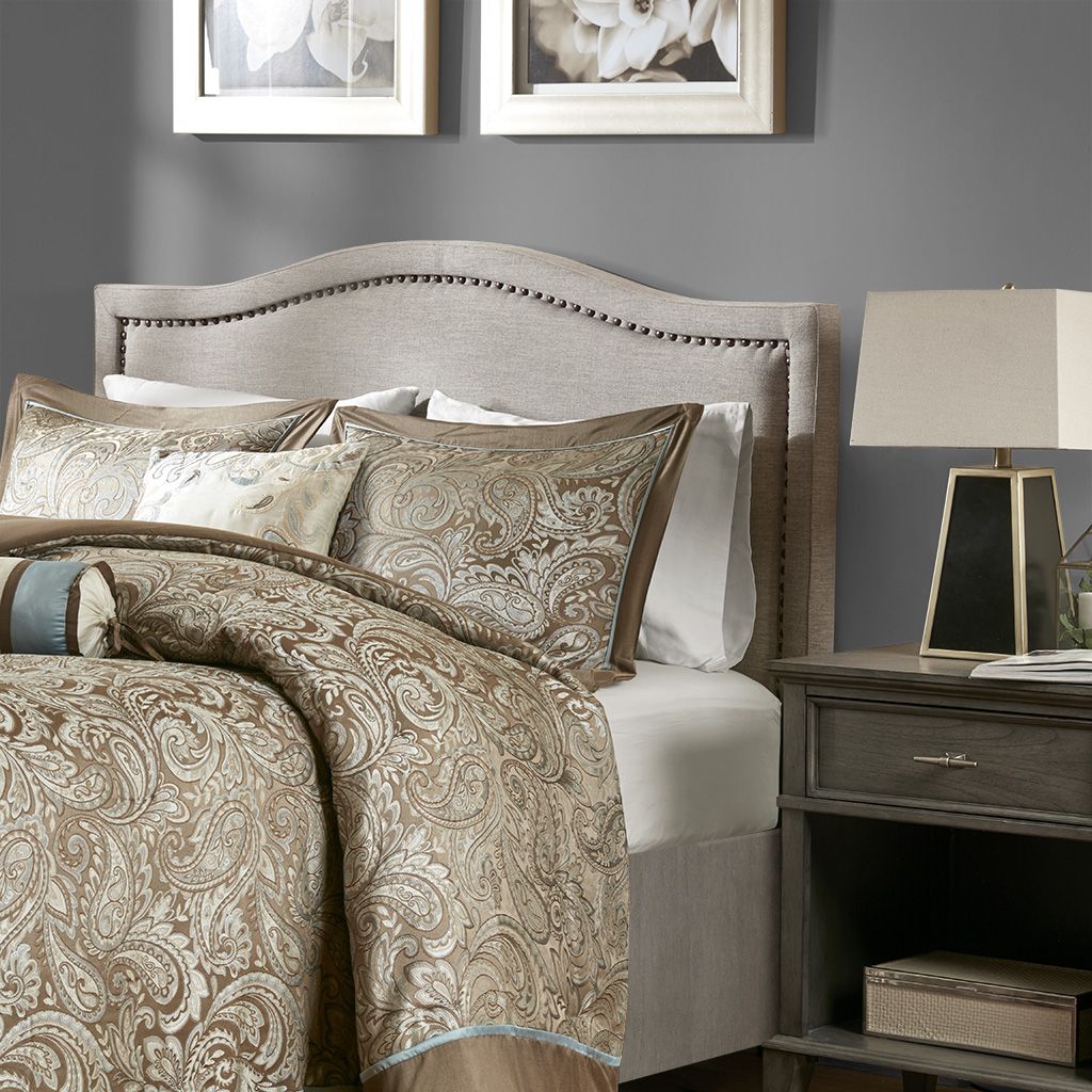 Upholstered beige headboard with nailhead trim, Doba brand, paired with paisley bedding