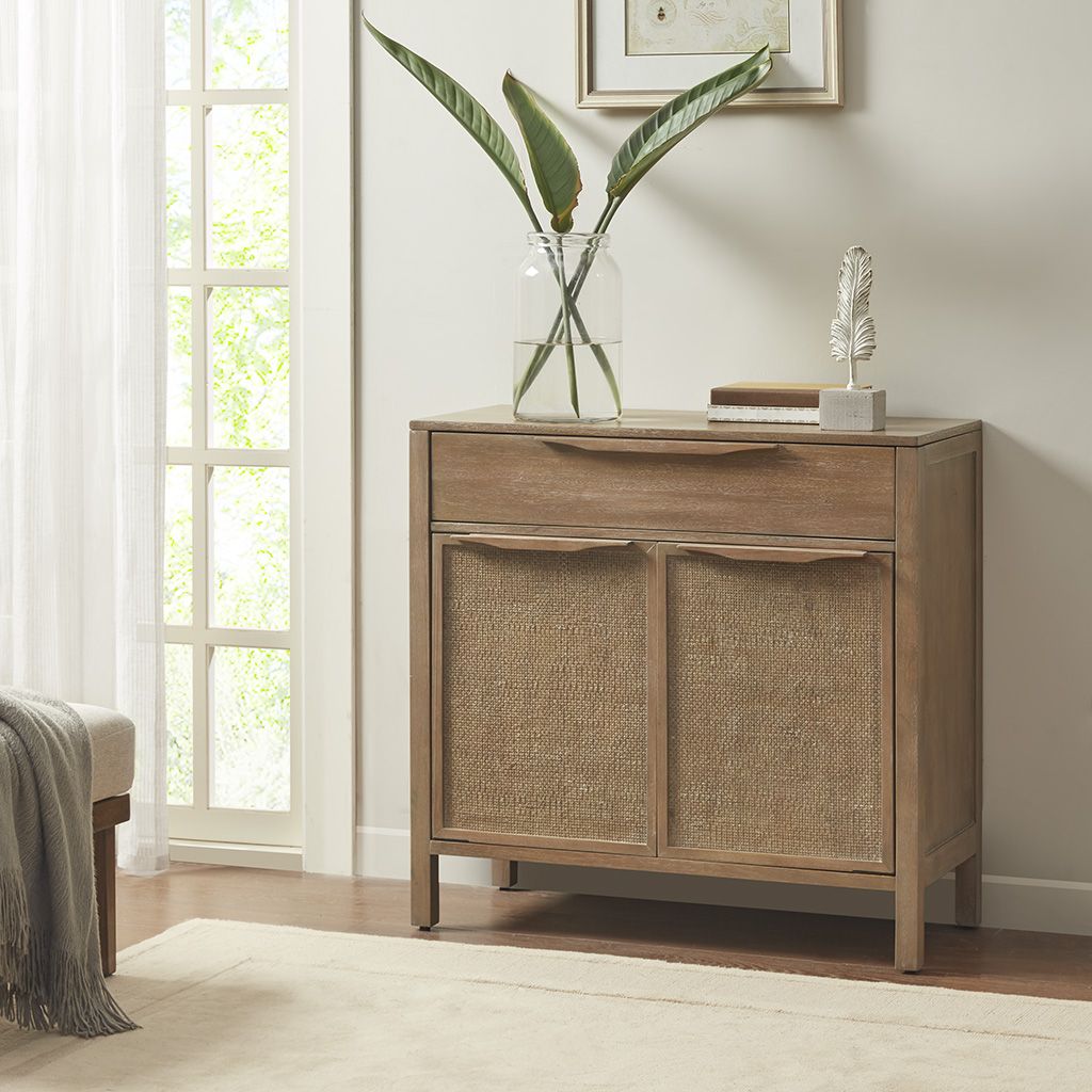 Accent chest in natural wood with woven rattan cabinet doors; glass vase with leaves on top, by Doba