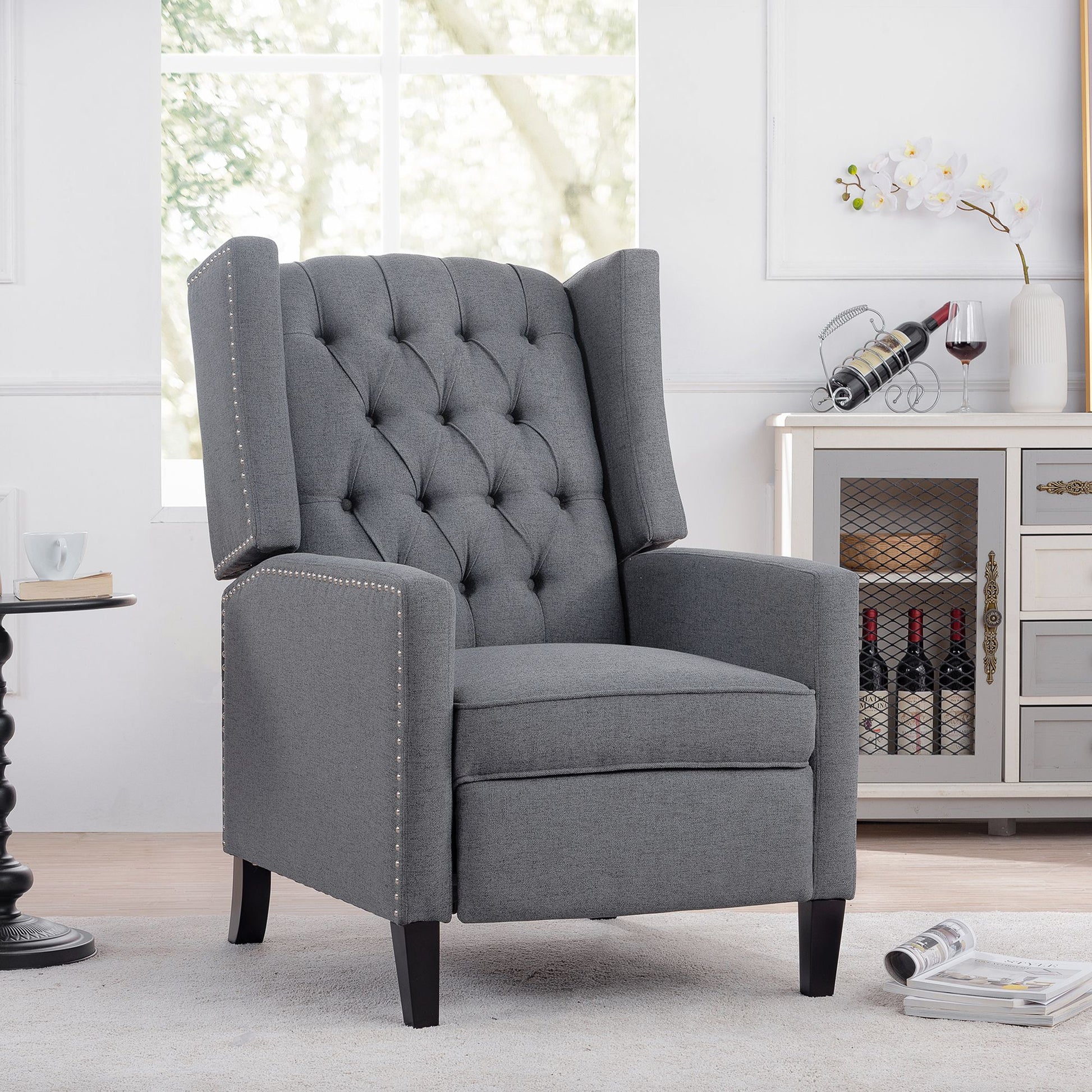 27.16-inch wide manual wing chair recliner in gray fabric with tufted back and nailhead trim.