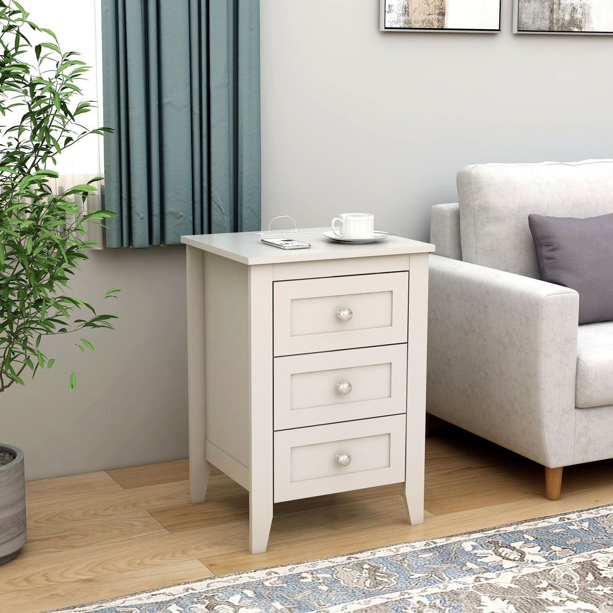 Doba white wooden 3-drawer nightstand with round metal knobs beside a gray sofa in the living room