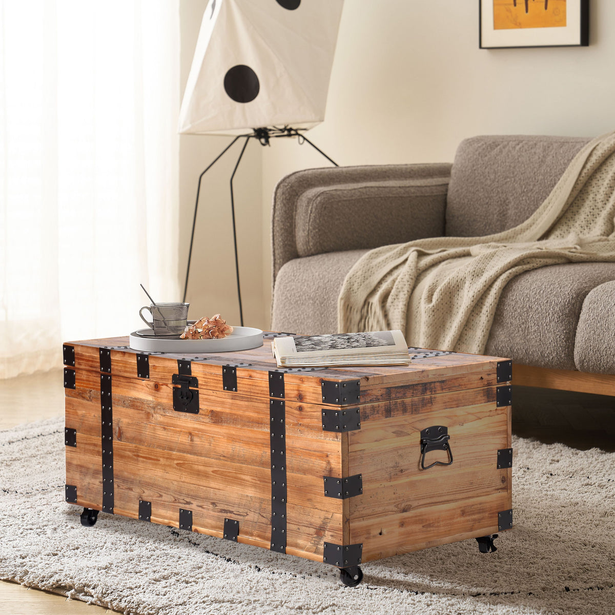 Trunk coffee table in natural reclaimed wood with black metal hardware, large storage, and four wheels