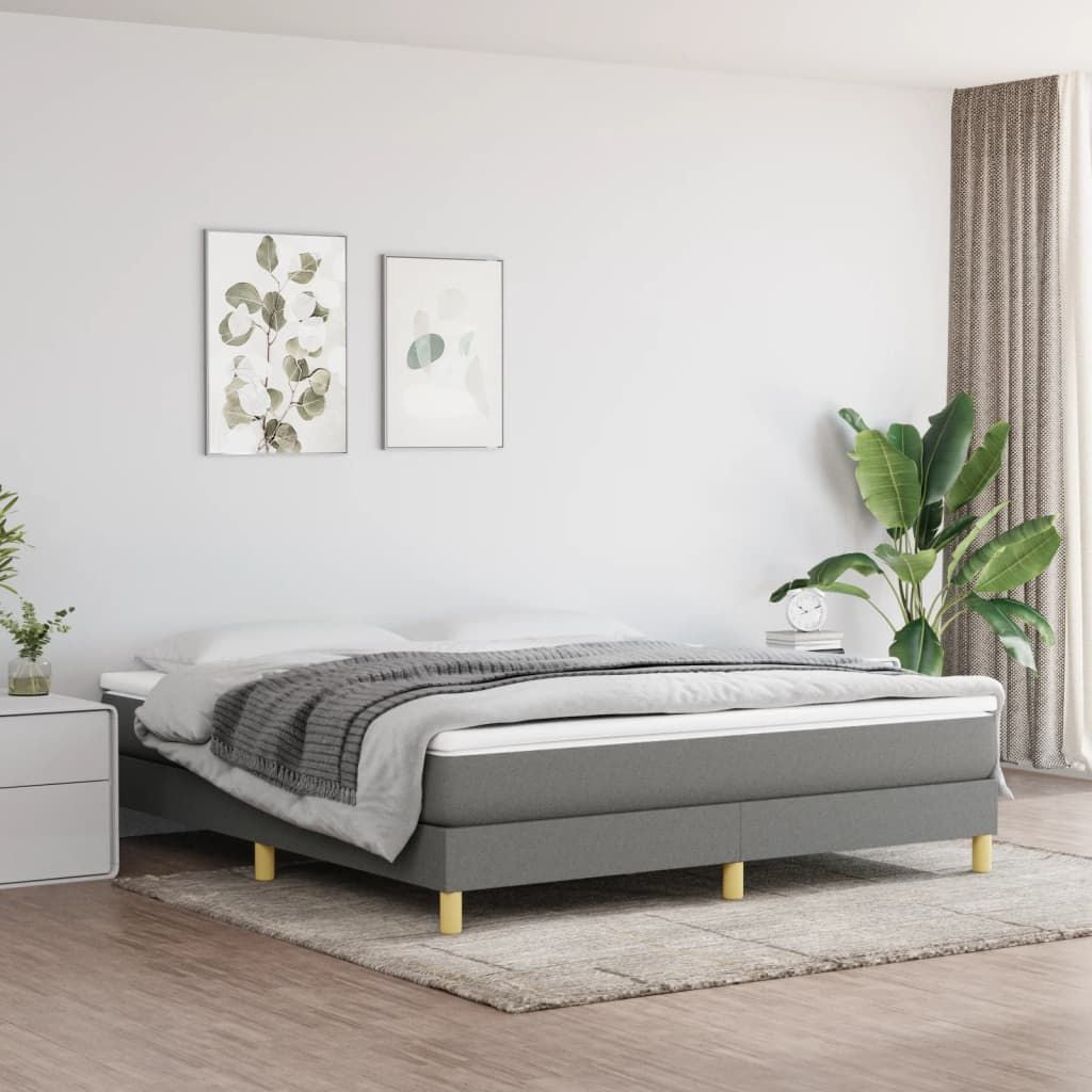 King bed frame with dark gray upholstered fabric and light wood legs in a modern bedroom.