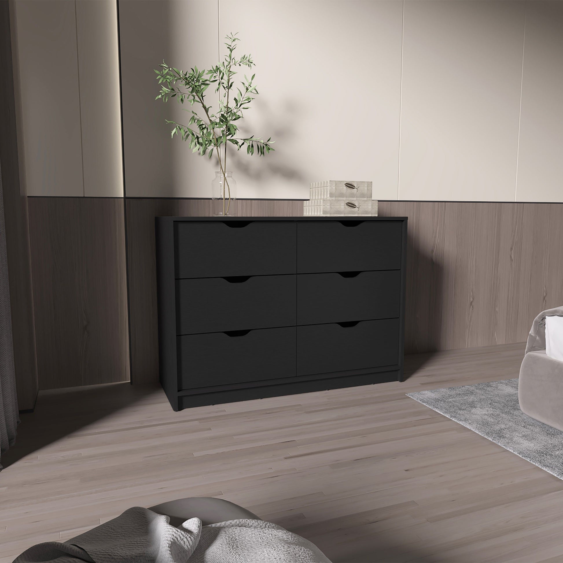 Black 4-drawer dresser with recessed handles in a modern bedroom, topped by a plant.