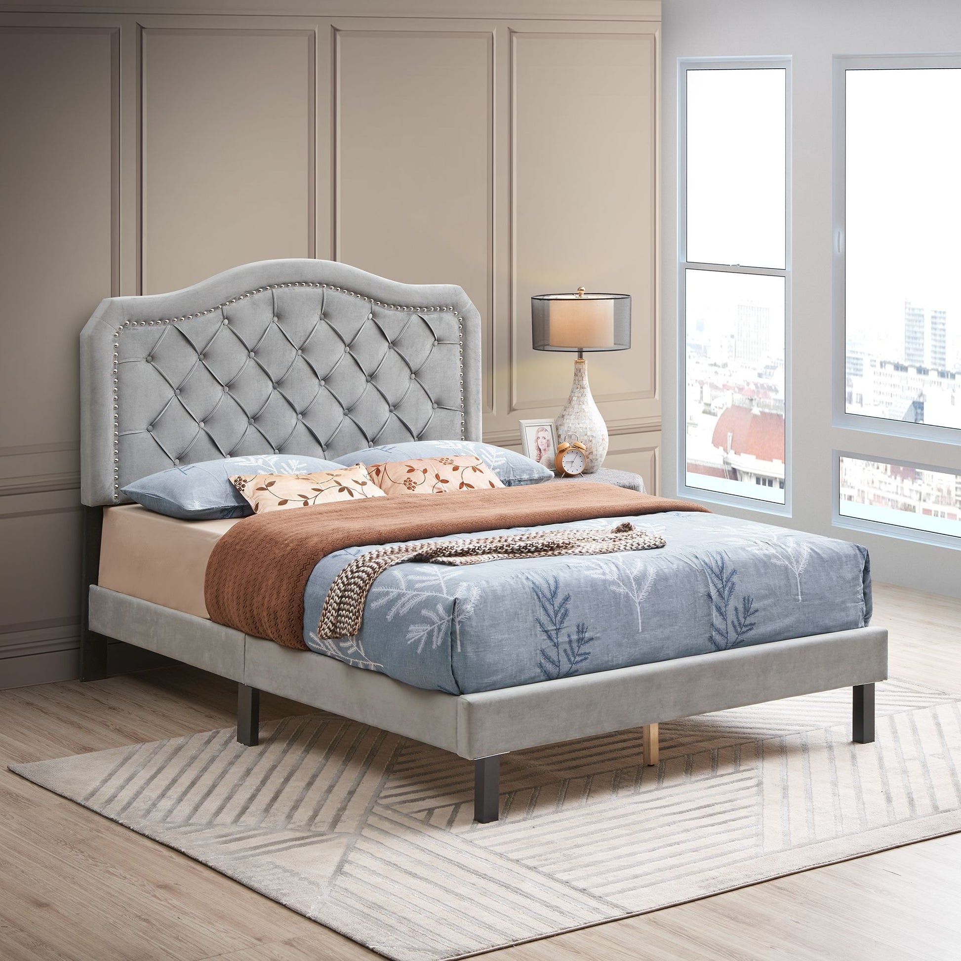 Upholstered bed with curved, button-tufted headboard and nailhead trim in gray velvet; queen size platform bed
