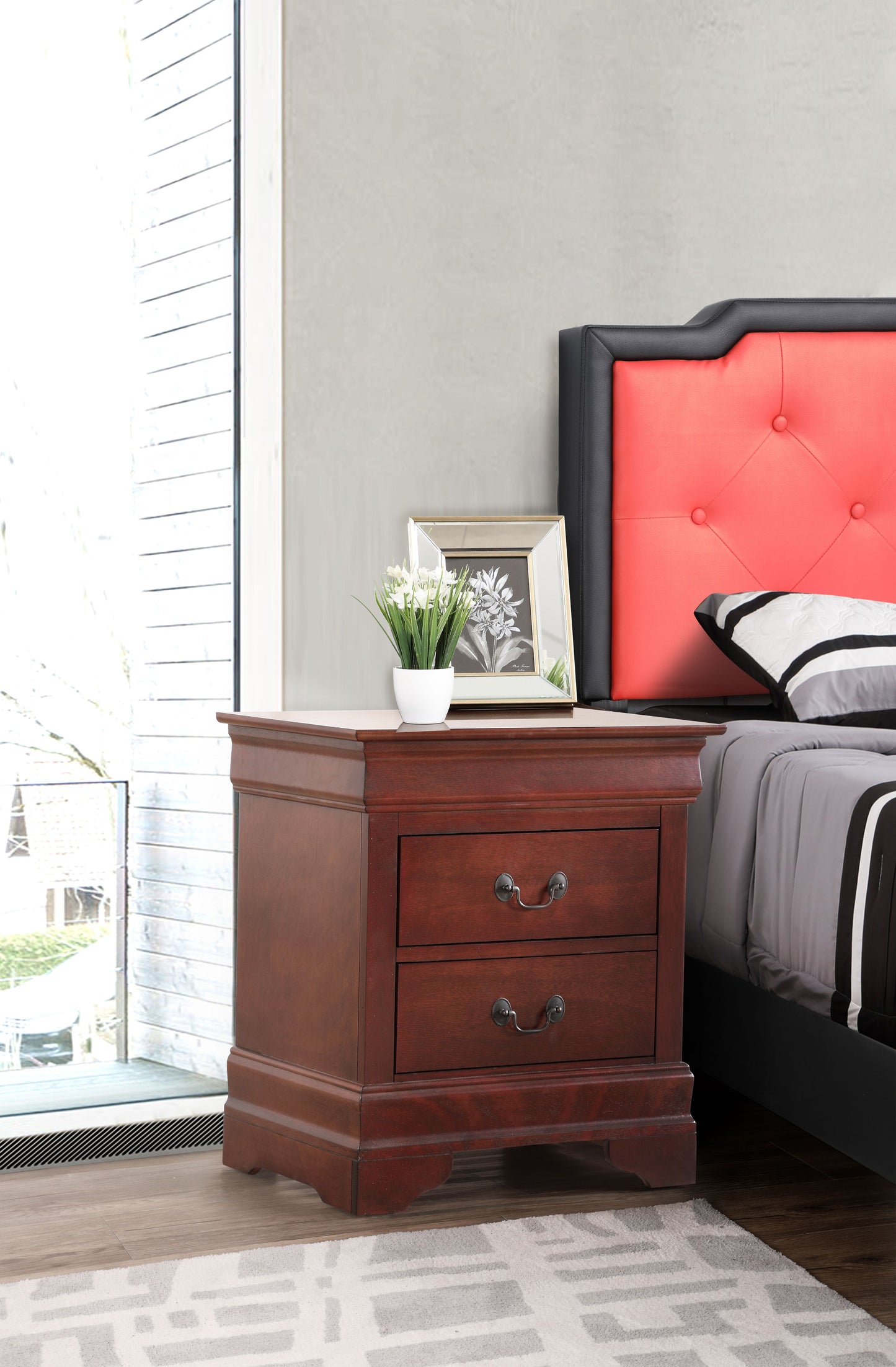 Elegant traditional cherry nightstand with drawer storage and metal pulls beside a red upholstered bed.