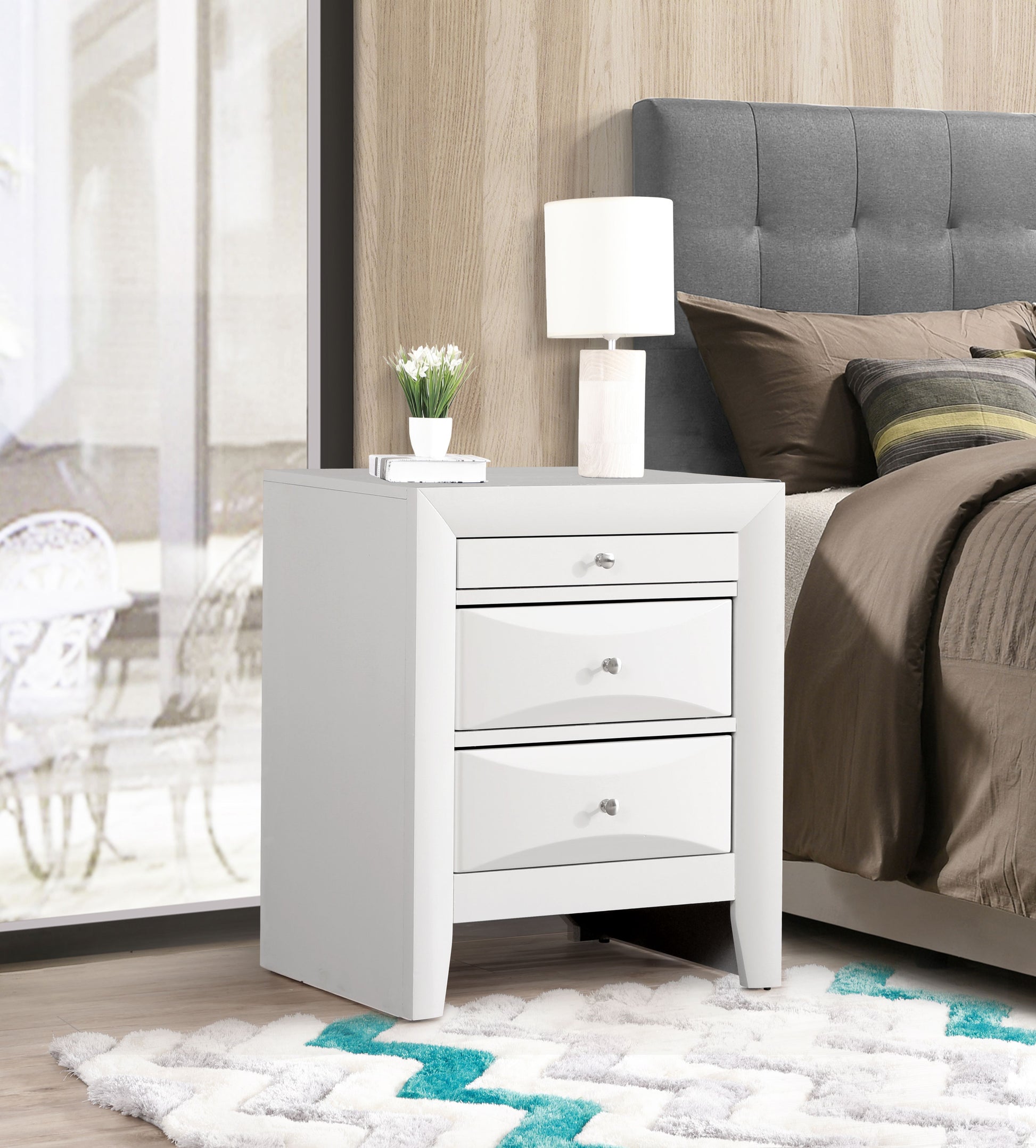 Elegant white nightstand with three drawers, modern bedside table in a contemporary bedroom with lamp and plant.