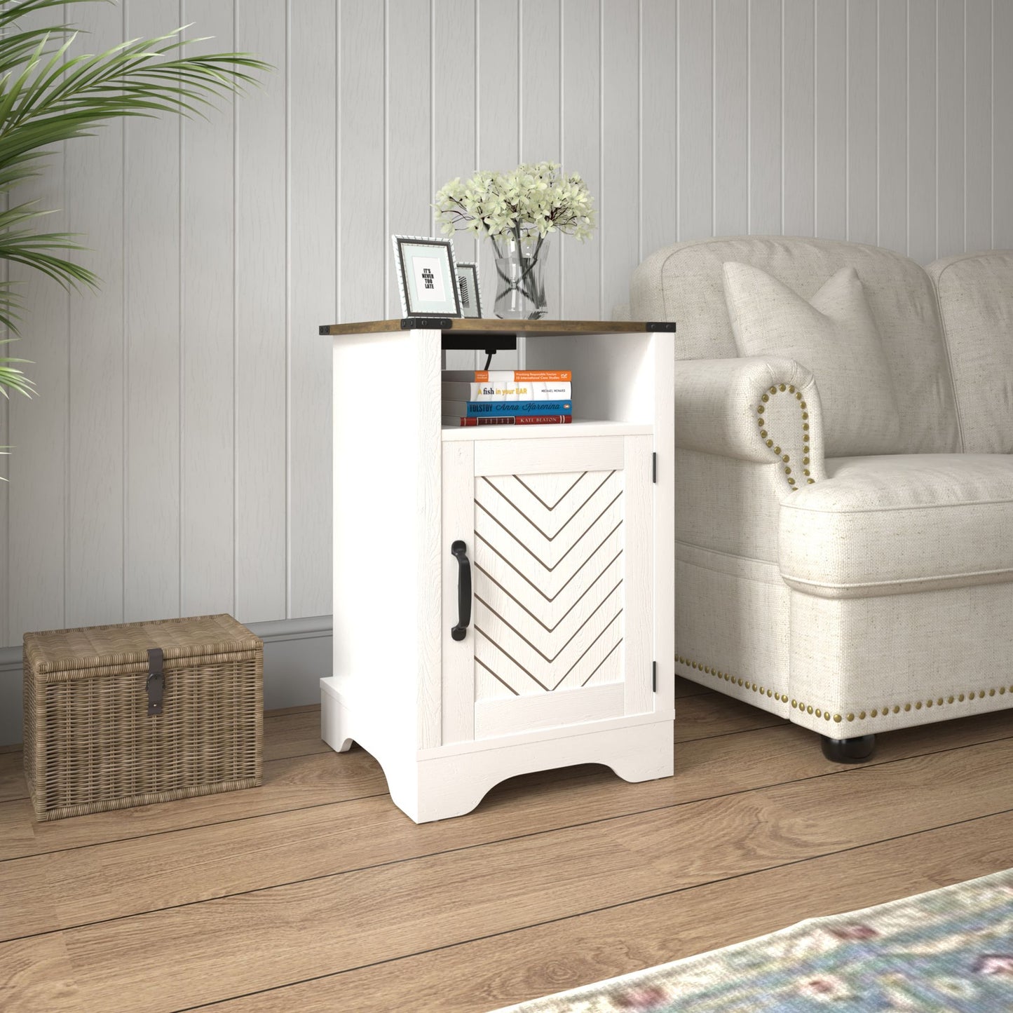 Farmhouse nightstand with white base and oak top, chevron-paneled cabinet door, black hardware beside a sofa.
