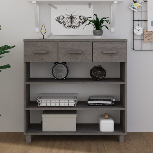 Three-drawer light grey solid pine and MDF console table with open shelves, featuring clock, plant and basket decor